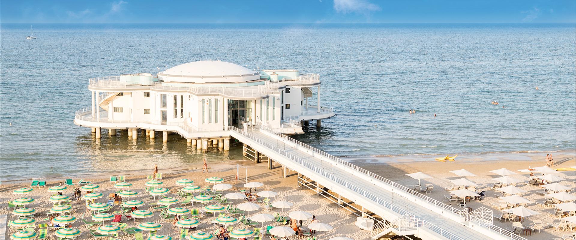 Spiaggia con ombrelloni colorati e un edificio sul mare.