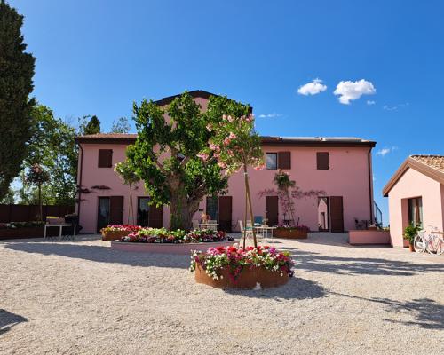 Casa rosa con giardino fiorito e cielo azzurro, ambiente tranquillo e sereno.