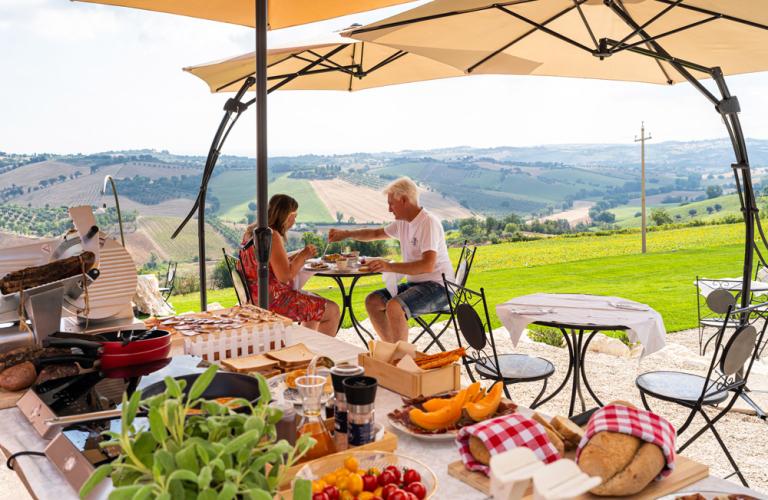 Colazione all'aperto con vista panoramica su colline e campi coltivati.