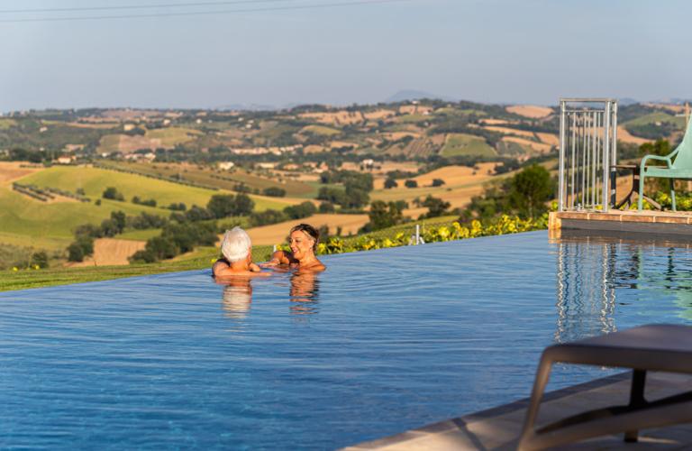 Donna sorridente in bikini, tenendo la mano vicino alla piscina.