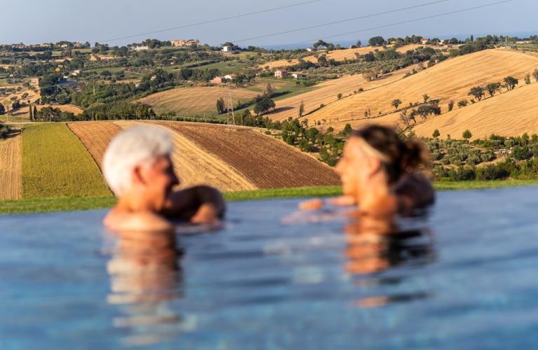 Piscina a sfioro con vista sulle colline e campi coltivati.