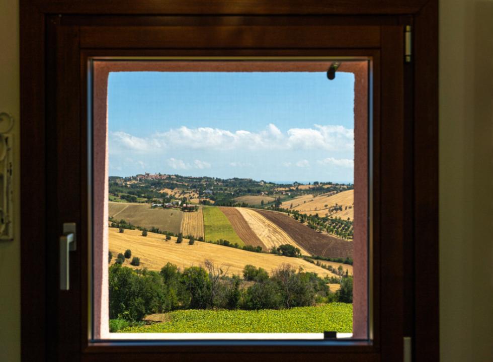 Terrazza con vasca idromassaggio e set da pranzo, vista su alberi e campagna.