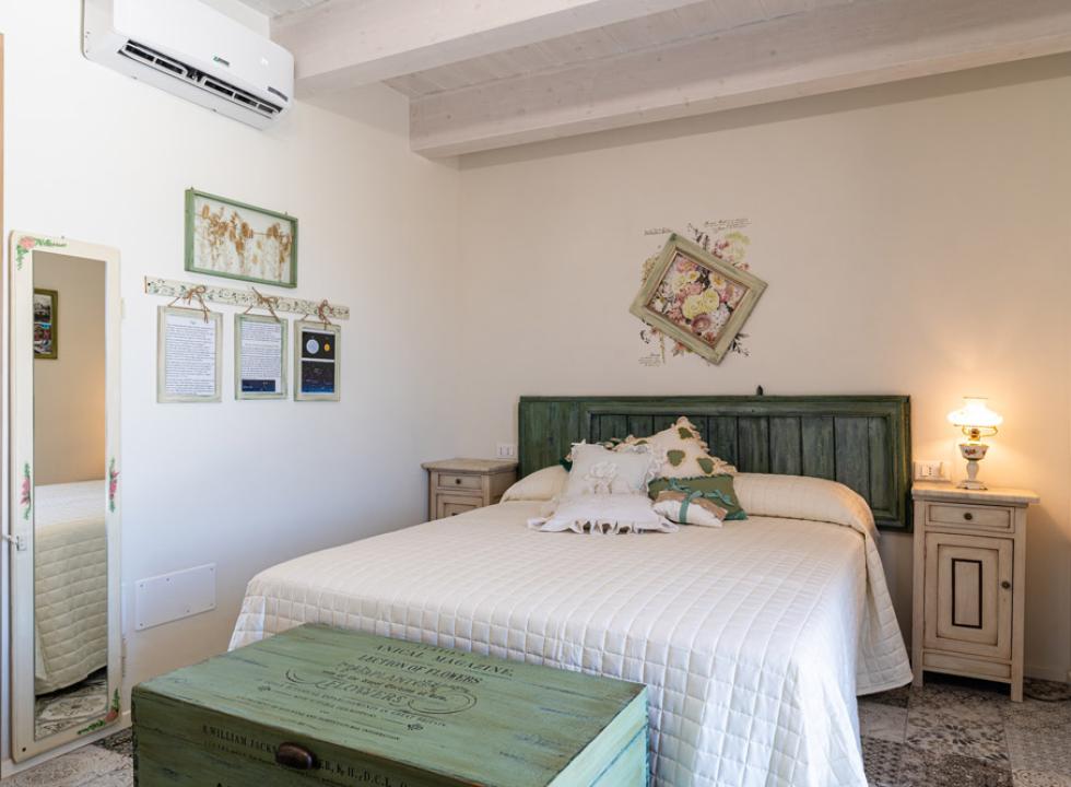 Camera da letto accogliente con lampadario, testiera verde e tende verdi.