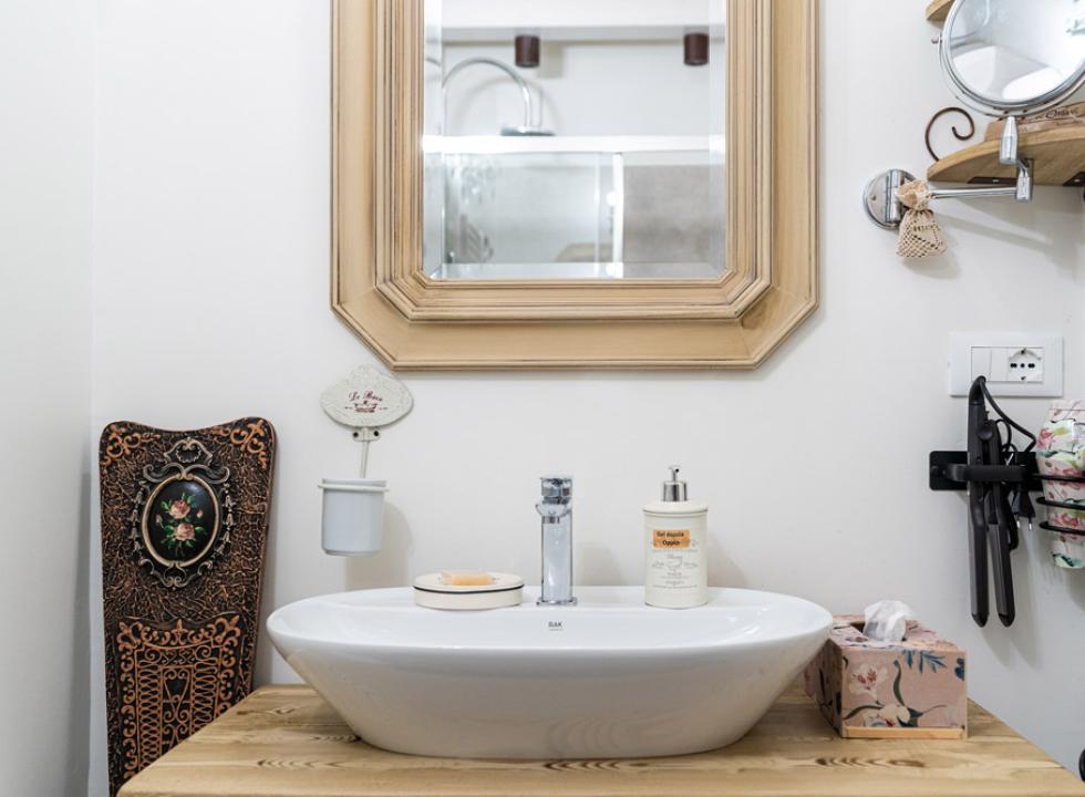 Bagno con specchio, lavandino, sapone, asciugacapelli e decorazioni vintage.